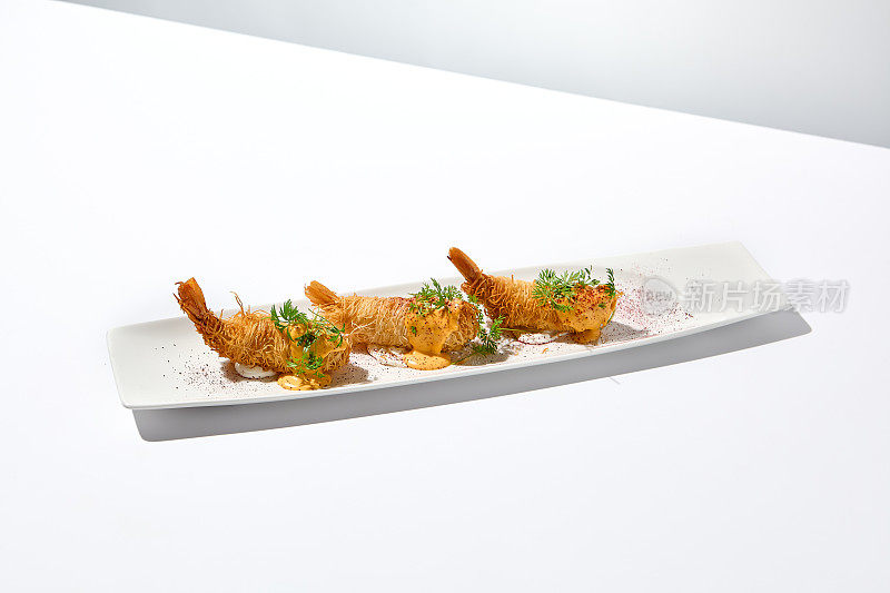 传统的希腊开胃菜- kataifi裹虾放在白色盘子里。夏日的kataifi酥皮虾。虾开胃菜，在kataifi面团里炸。现代风格的脆虾。